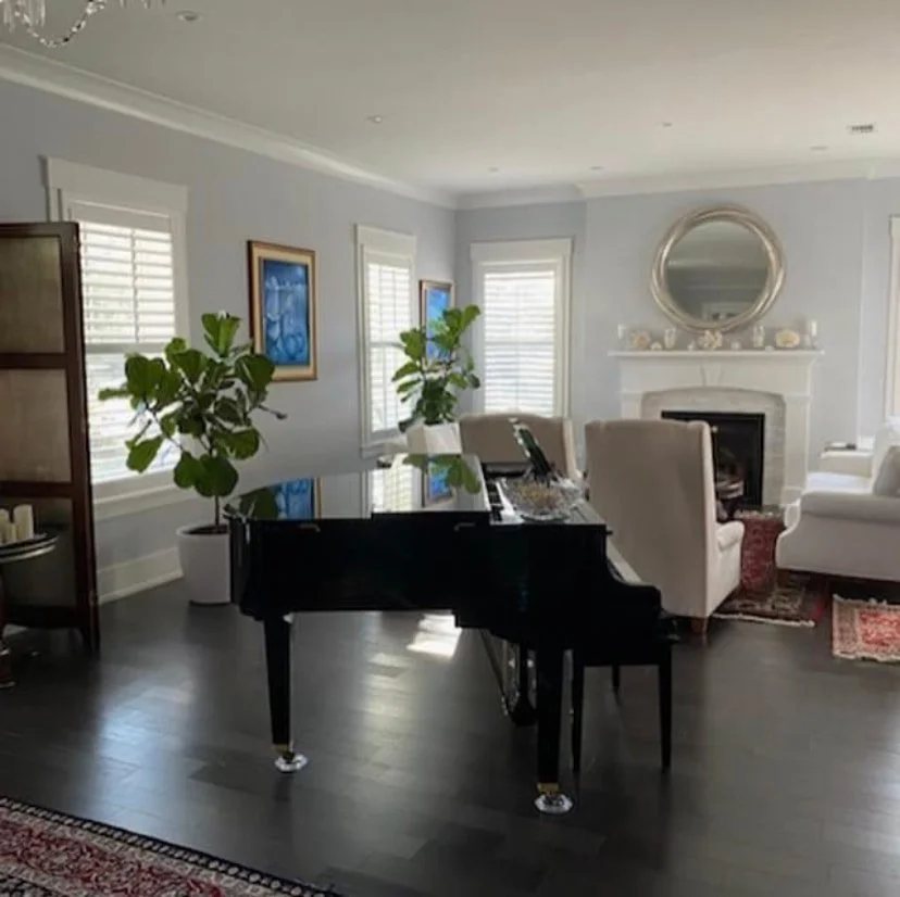 Formal living room with a grand piano and plantation shutters