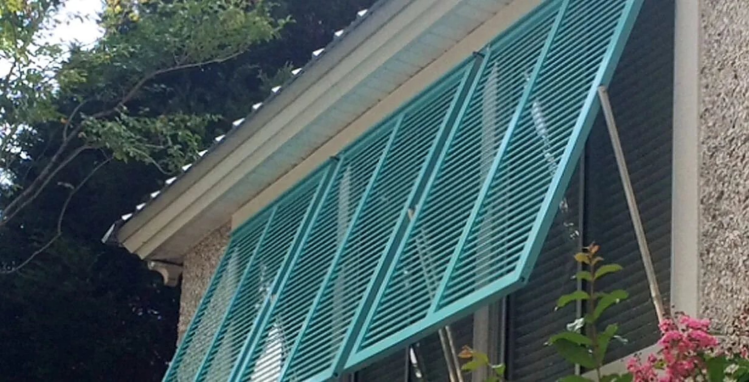 Blue Bahama hurricane shutters on a coastal home