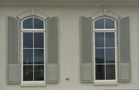 Decorative raised panel and louvered Colonial hurricane shutters on a home exterior