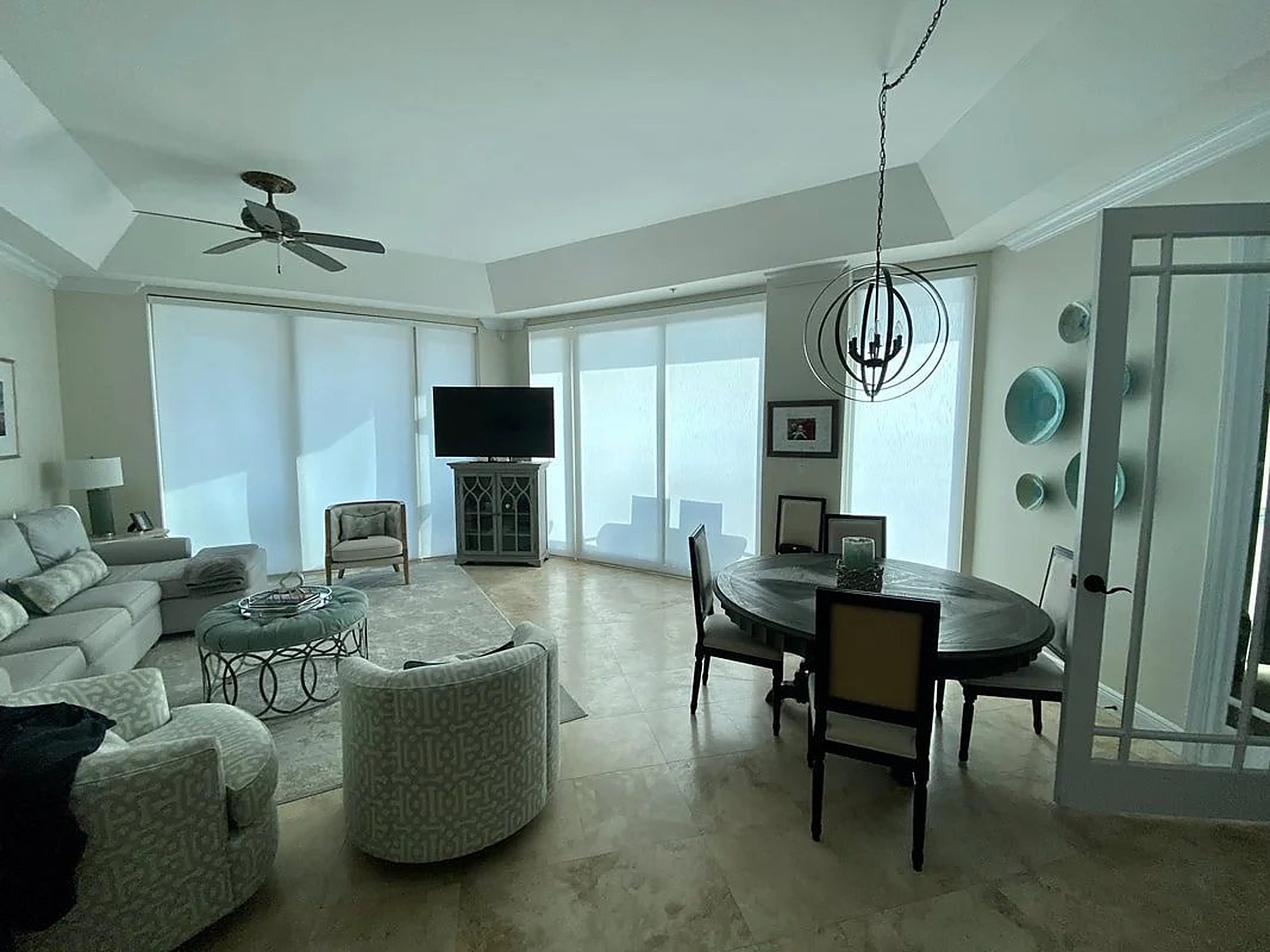 Coastal living room where drapery layers over roller shades